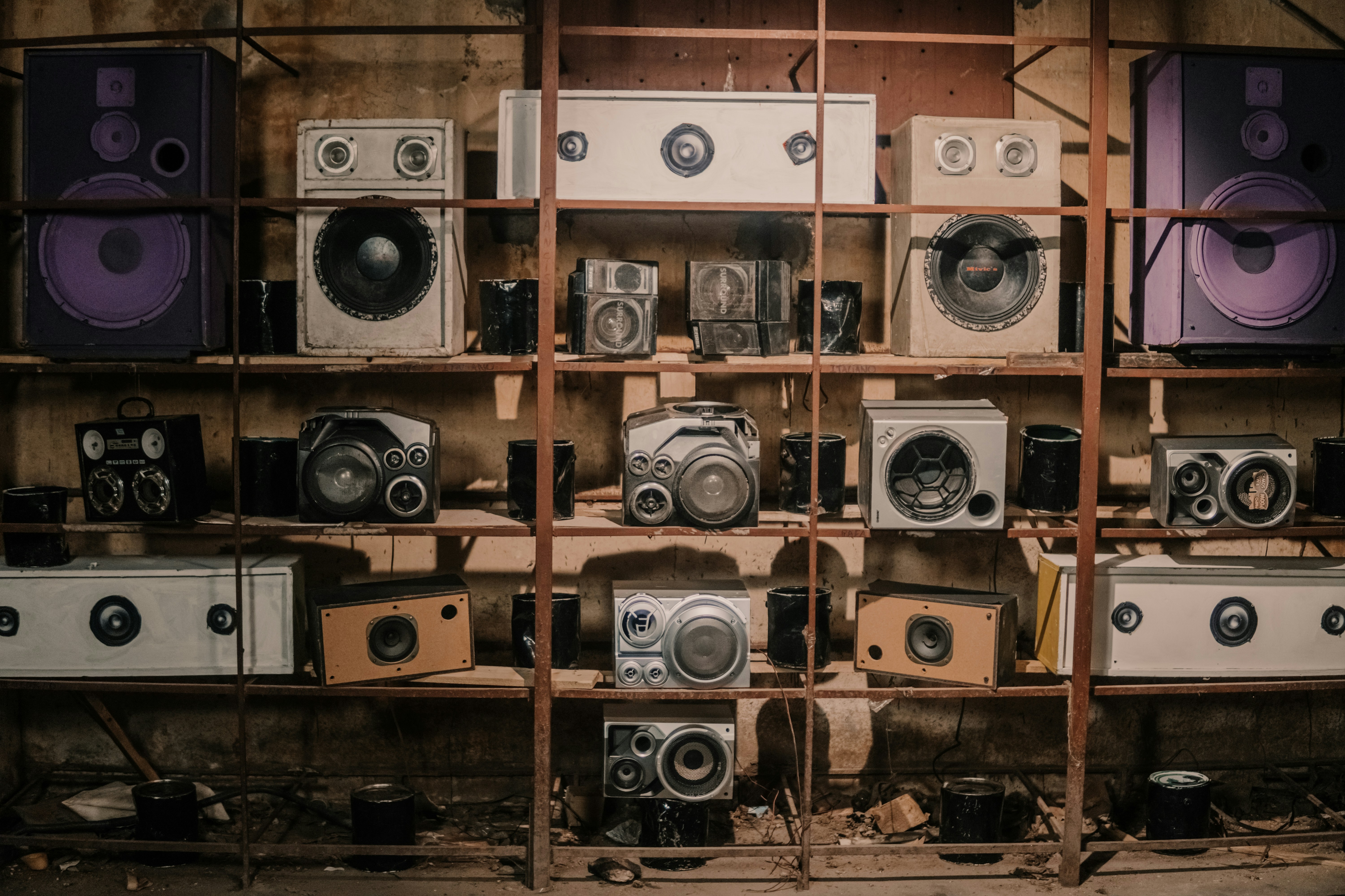A wall of vintage speakers stacked on rusted shelves